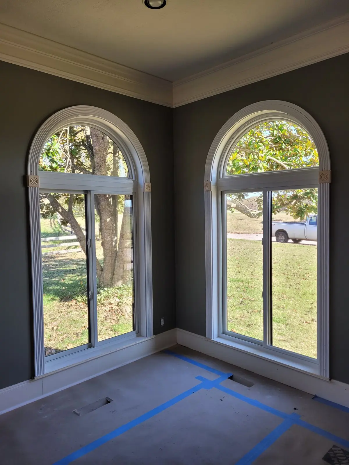Two arched windows mid-install with painter's tape still on the floor