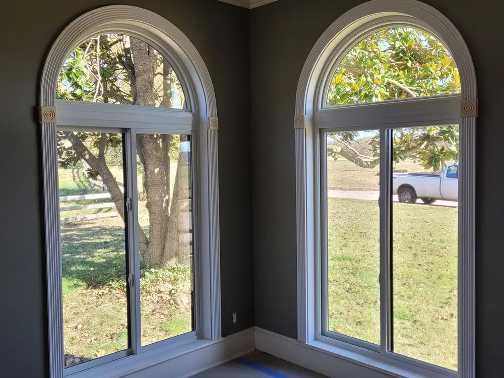 Two arched windows mid-install with painter's tape still on the floor