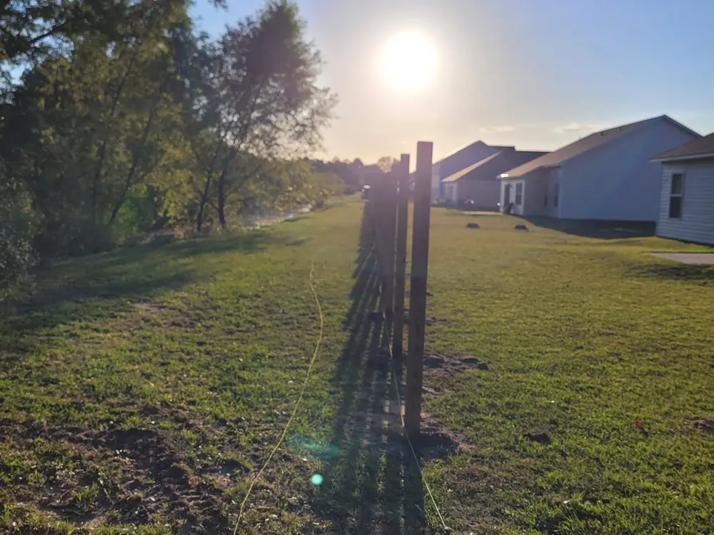 Fence posts set on a string line across a back yard