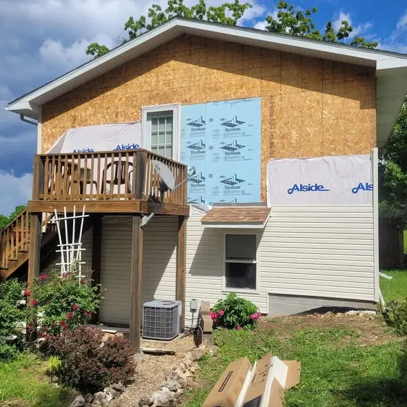 Old siding removed showing sheathing, house wrap, and insulation board