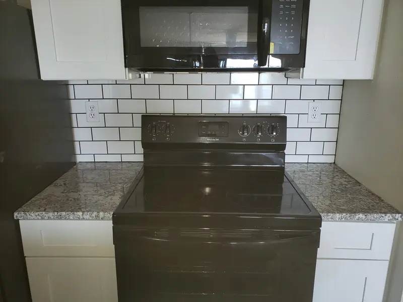 White subway tile backsplash behind a range with an over-range microwave